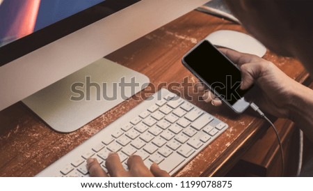 young man using and looking at smartphone in office