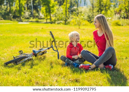 Mom and son rest on the lawn after riding a bike.