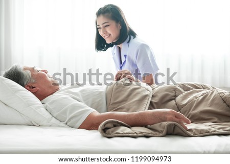 Senior man in bed and nurse woke him up. Old asian man and beautiful asian nurse woman in bedroom and open curtain. Senior home service concept. Close up shot. Royalty-Free Stock Photo #1199094973