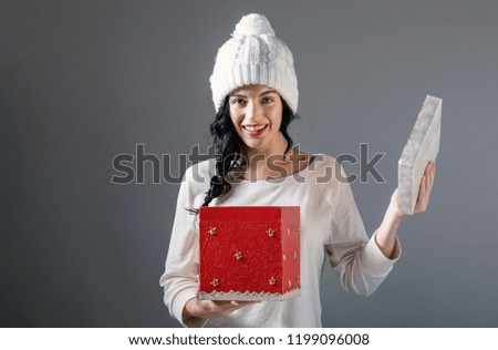 Young woman opening a Christmas present box on a gray background