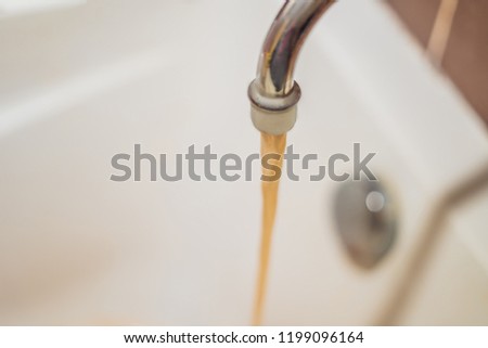 Dirty brown running water falling into a white sink from tap. Environmental pollution concept. Royalty-Free Stock Photo #1199096164