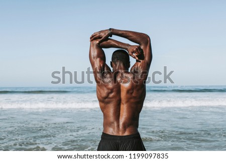 Fit man stretching at the beach Royalty-Free Stock Photo #1199097835