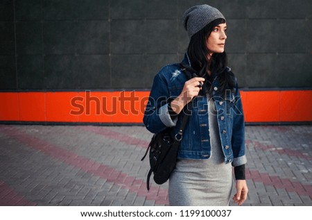 Stylish young girl in  gray dress walks on  street.