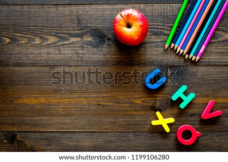Elemerntary school concept. Letters of toy alphabet, apple and color pencils on dark wooden background top view copy space