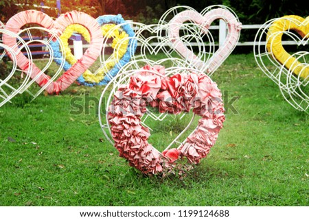 
Heart shape made of steel and fabric on the green grass and sunlight background