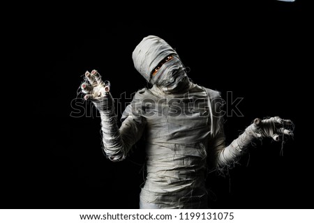 Studio shot portrait of young man covered by cloths in costume dressed as a halloween cosplay of scary mummy pose  acting on isolated black background. Royalty-Free Stock Photo #1199131075