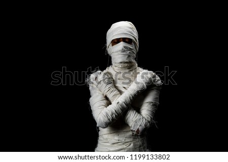 Studio shot portrait  of young man in costume  dressed as a halloween  cosplay of scary mummy pose like close eye and cross his arm acting standing on isolated black background.