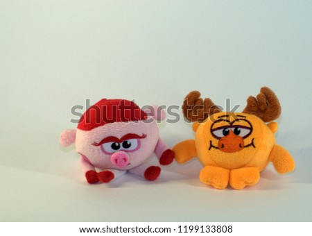 Small soft children's toys depicting a baby pig and moose. The picture was taken in close-up on a white background.
