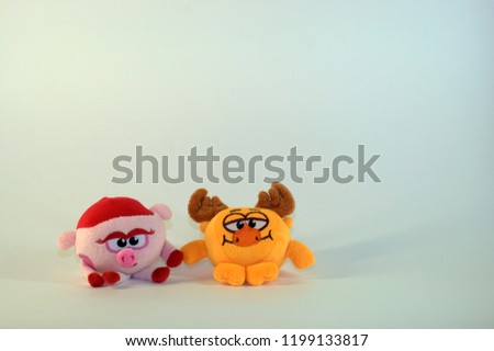 Small soft children's toys depicting a baby pig and moose. The picture was taken in close-up on a white background.
