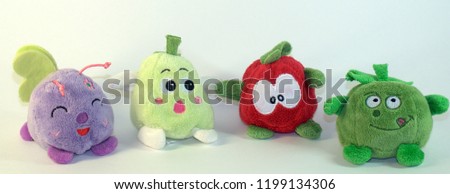 Small soft children's toys depicting fruits, vegetables and a small fly. The picture was taken in close-up on a white background.

