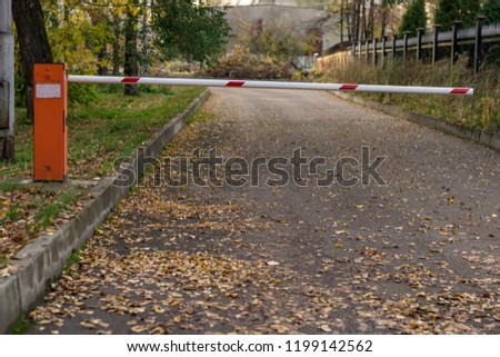 the barrier on the road leading to the building on the background of fallen autumn leaves