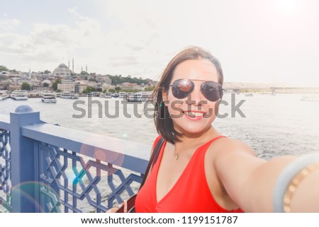 Beautiful Chinese woman takes selfie with view of Suleymaniye Mosque and Bosphorus in Istanbul,Turkey