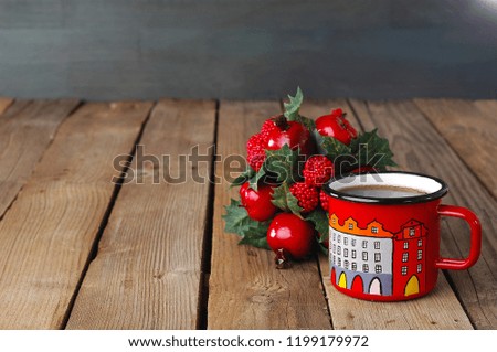 tea in a red enamel cup next to aChristmas ornament, wooden background, space