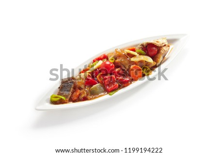 Fried Fish with Vegetables in Sweet and Sour Sauce on Elegant Restaurant Plate Isolated on White Background. Whole Chopped Sea Bass with Stewed Tomatoes, Sweet Pepper, Carrots and Onions Close Up