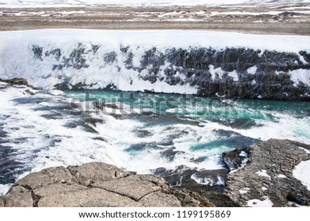 Gullfoss Waterfall on the Hvita river, Iceland. Rocky foreground, fast flowing water and snowy, frozen ravine