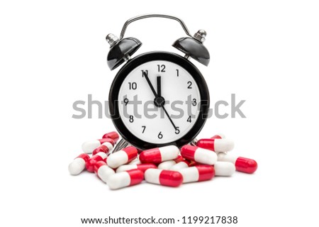 Clock with red-white capsules on white background.