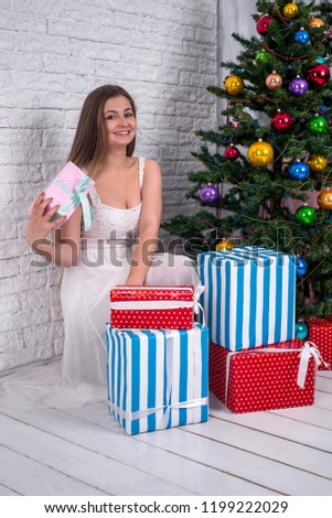 Attractive blonde woman with fir-tree and gift boxes