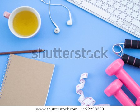 Two pink dumbbells hand exercise measurement tape notebook cup of tea and keyboard put on blue pastel background in top view and have free space for insert text,this accessories for sports activity