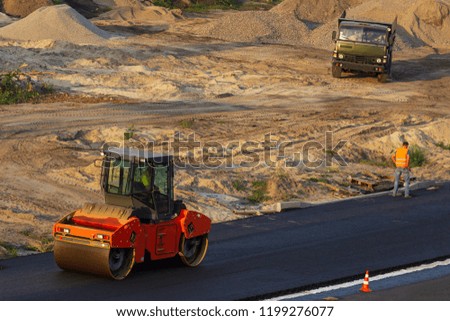 industrial landscape with rollers that rolls a new asphalt on the road. Repair work, complicated transport movement.