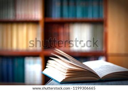 Open book on a table,on the background of bookshelves Royalty-Free Stock Photo #1199306665