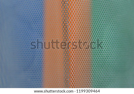 Colorful papers which are blue, orange and green with partial focus of the grid pattern of paper bin that design as modern background and wallpaper.