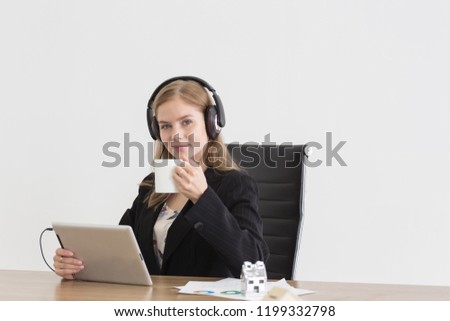 Relaxing Young business woman with headphone and white cup workday to music in office building looking at the camera over white background