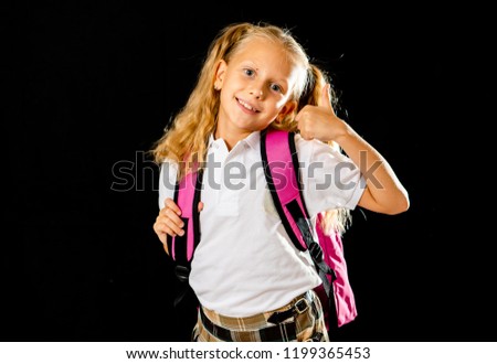 Adorable beautiful little schoolgirl with big pink schoolbag feeling excited and happy isolated on a black background in back to school end of the year and children education concept.