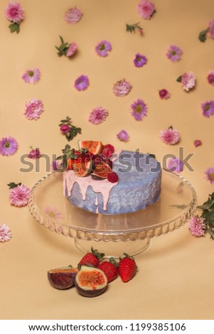 Blue cake with fruts on beige background decorated with flowers