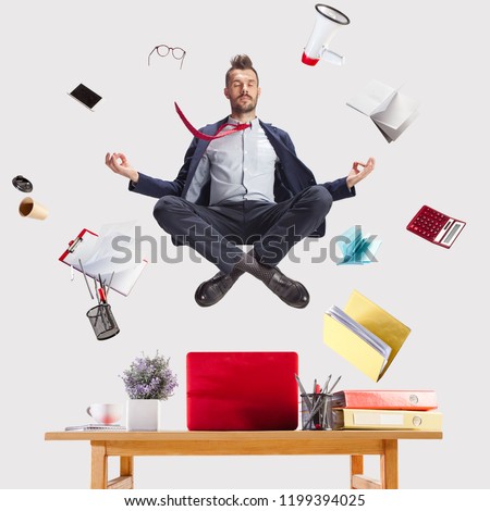 The young zen businessman relaxing at office in yoga pose lotus, while his work is doing. levitation concept