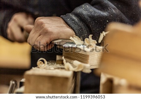 Eco friendly woodworker's shop. Details and focus on the texture of the material, saw dust, and planers or chisels, while making legs for a designer coffee table. Mastering wood with peacefullness. Royalty-Free Stock Photo #1199396053