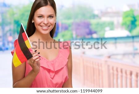 Happy Young Woman Holding German Flag against a street background