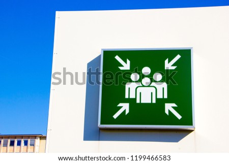 Pictogram of an assembly point outside at a parking area to assemble people from the buildings and offices in case of an emergency or a fire to keep everyone secure and safe.  Royalty-Free Stock Photo #1199466583