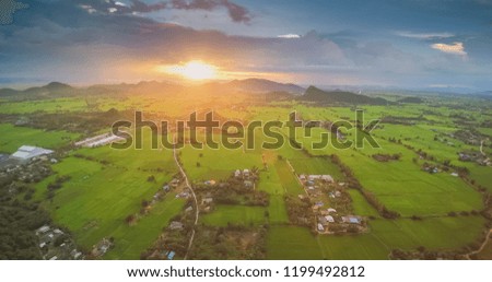Aerial view evening above the green rice fields with cloudy sky background, sunset at Wat Khao Chong Pran ( Bat Temple ), Ratchaburi, Thailand