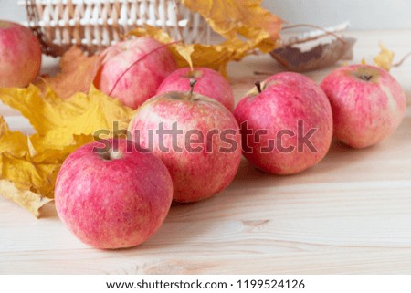 ripe red apples on a wooden table with autumn leaves and wicker basket
