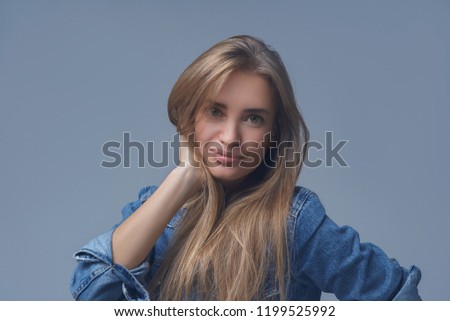Young woman with beauty skin and beauty hairstyle in jeans jacket isolated on blue background. Studio shot.