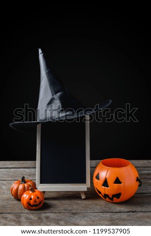 Halloween background. chalkboard on the stand, Witch hat with Halloween Pumpkins on wooden floor and black background