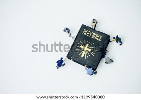 Miniature people : Worker try to fix and open Holy bible on white background.body of christ and church bible study group concept.