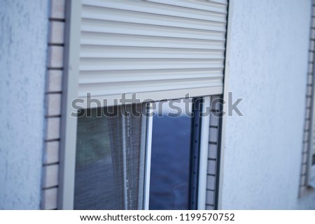 Window with half-closed roller shutter, closeup