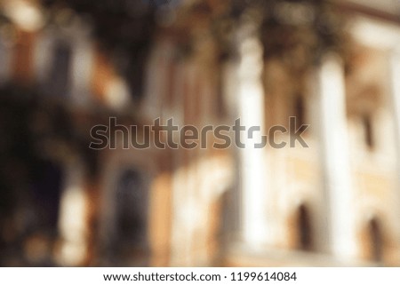 A blurred background in shades of beige. An old house with white columns is out of focus.