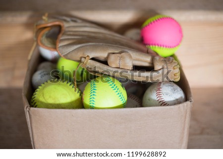 A box full of baseballs and a baseball glove.