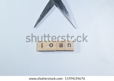 A picture of word tiles create the word loan and scissors. It is a symbolic of loan cutting.