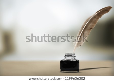 Quill pen with inkwell on wooden desk.
