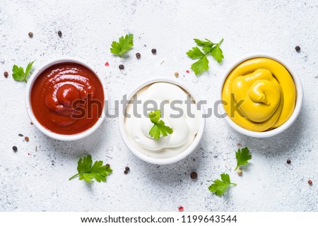 Set of sauces - ketchup, mayonnaise and mustard on white background. Top view. Royalty-Free Stock Photo #1199643544