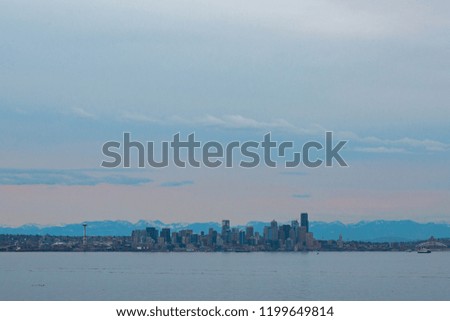 Seattle Skyline Cityscape over water at sunset with mountains in background