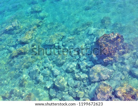Clear bright blue or turquoise ocean water with light patterns on the stones of the ocean floor