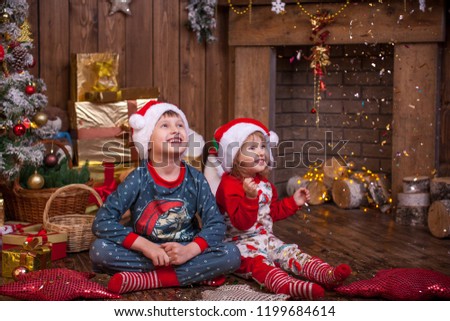 Christmas. children in pajamas admiring the Golden serpentine. They admire the magic of the holiday. Christmas is a mysterious and wonderful time