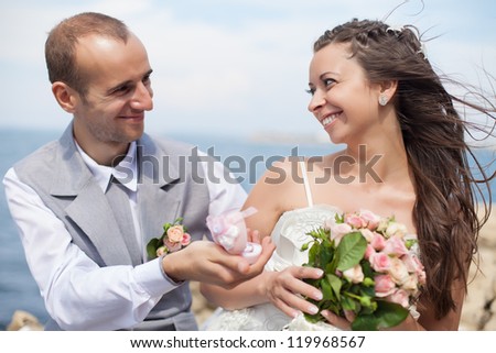 Beautiful bride and groom celebrate their wedding. The groom holds a ring in his hand.