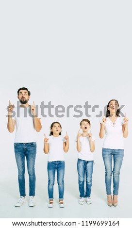 Beautiful family standing in line and pointing up and shouting isolated on white background