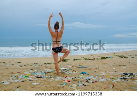 A young woman in a swimsuit doing ballet on a beach, surrounded by trash, Ada Foah, Ghana.