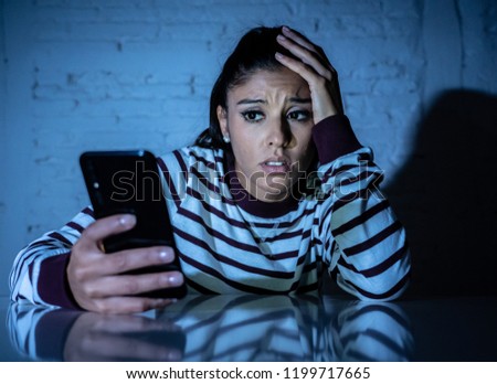 Frightened teenager or young woman using smart mobile cell phone as internet cyberbullying by message stalked abused victim. Royalty-Free Stock Photo #1199717665